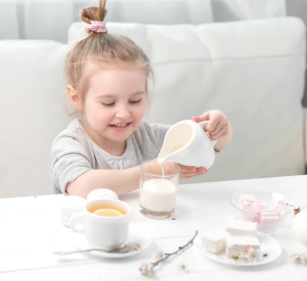 어린 소녀 그녀의 찻잔에 우유를 붓는 — 스톡 사진