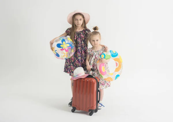 Sad sisters are standing near a suitcase — Stock Photo, Image