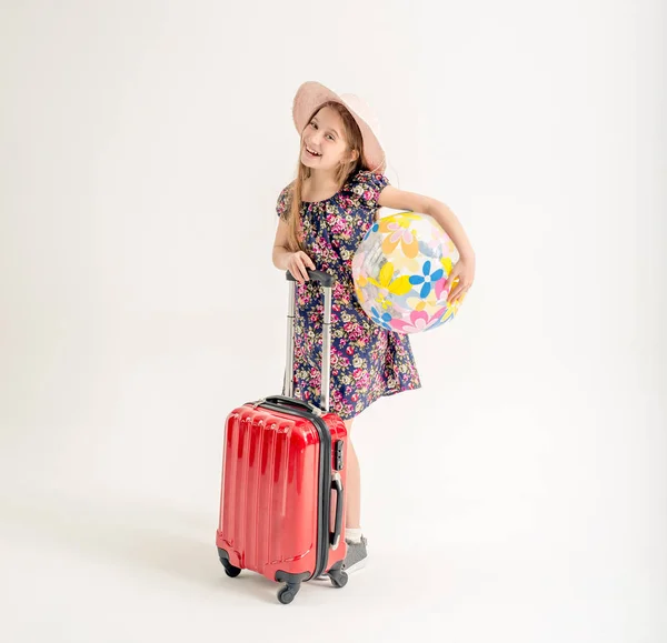 Happy little girl is standing near a suitcase — Stock Photo, Image