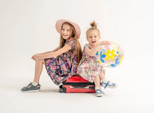 Irmãs felizes estão sentadas em uma mala — Fotografia de Stock