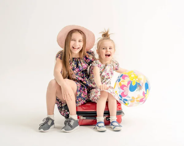 Irmãs felizes estão sentadas em uma mala — Fotografia de Stock