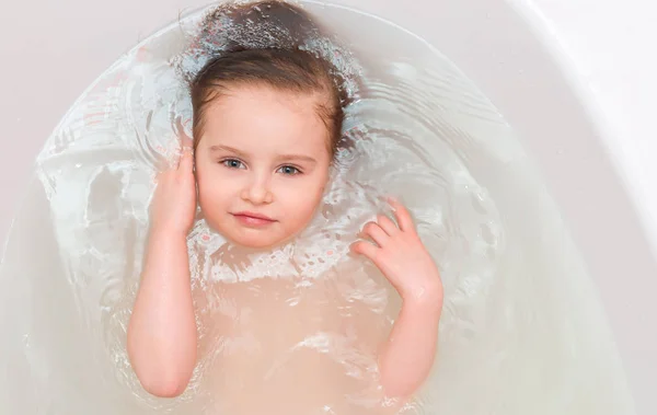 Adorable kid with long dark hair bathing, topview — Stock Photo, Image