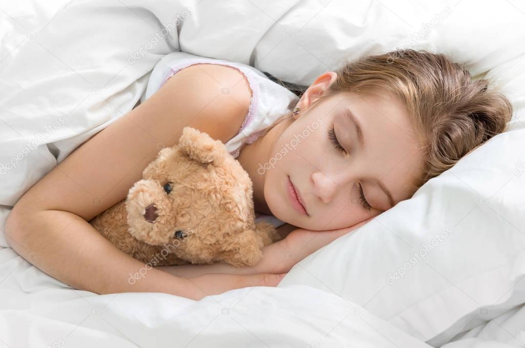 child hugging her teddy bear in sleep