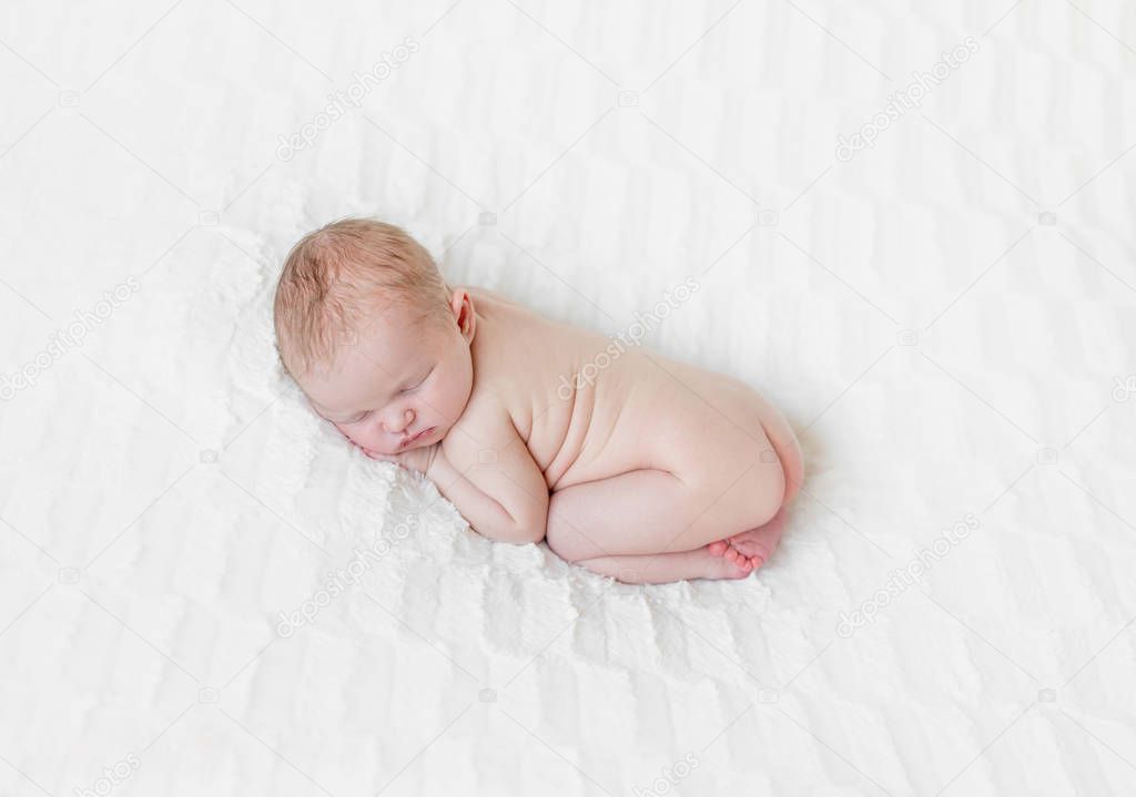Adorable naked infant sleeping on his belly