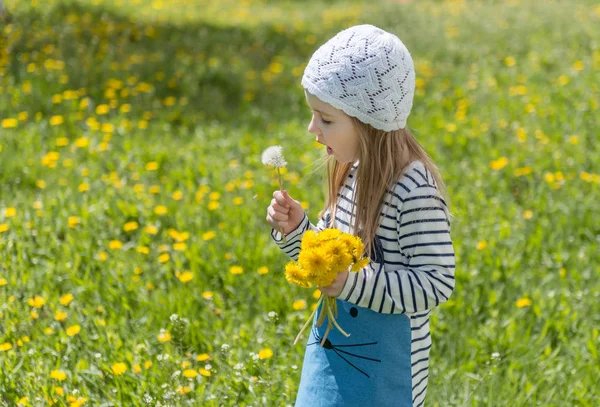 Liten flicka som leker med gula blommor utanför — Stockfoto