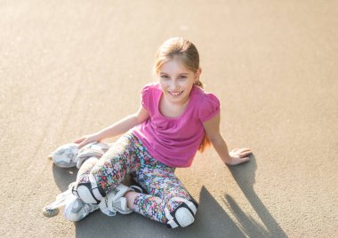 asfalt üzerine oturan, germe kız paten