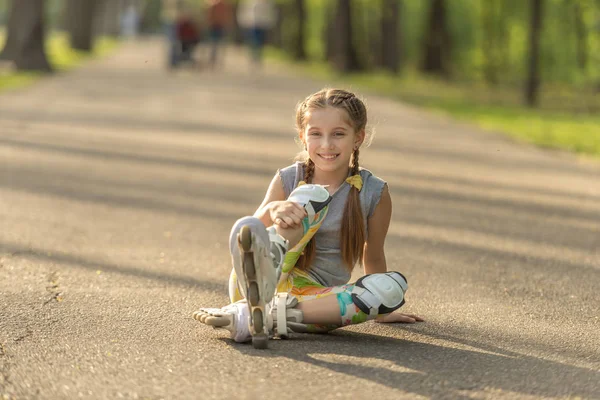 Adolescente chica patinaje, sentado en asfalto y descanso — Foto de Stock