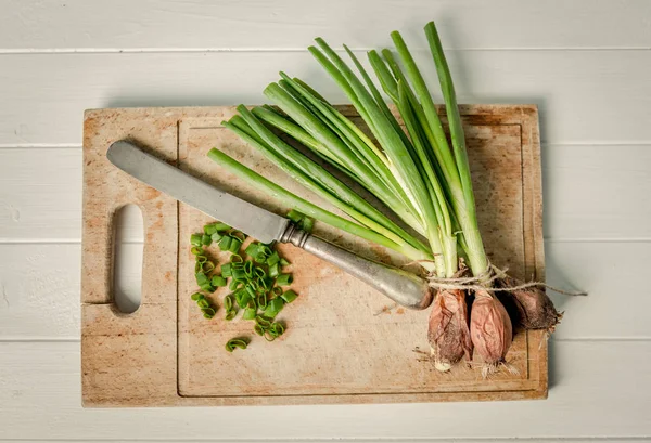 Schmutzige grüne Zwiebeln an Bord, Draufsicht — Stockfoto