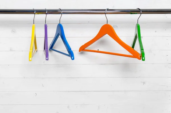 Multicolored hangers near the white brick wall — Stock Photo, Image