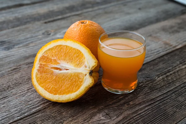 Apelsin och glas saft på bord — Stockfoto