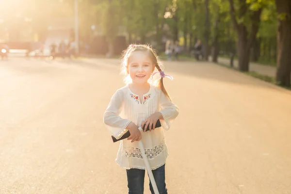 Dívka v vyšívané košile hrát s koloběžkou — Stock fotografie