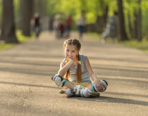 Adolescent fille patinage, assis sur l'asphalte et au repos — Photo