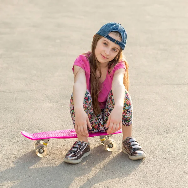 Girl with long hair sitting on skating board — Stock Photo, Image