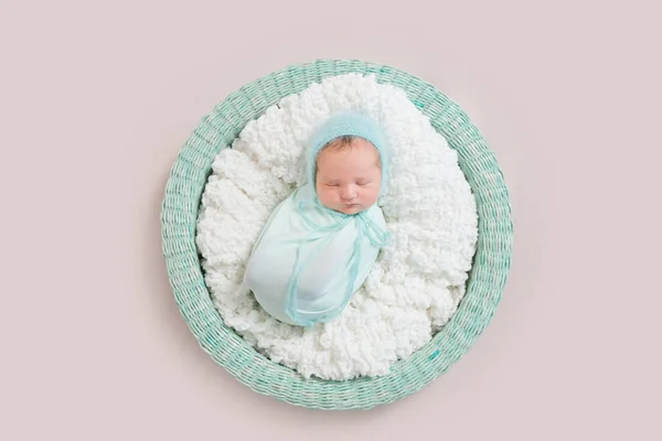 baby wrapped in blue blanket in basket, topview