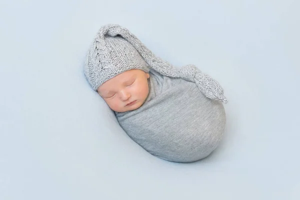 Bebê adorável com chapéu cinza de malha, cochilando — Fotografia de Stock