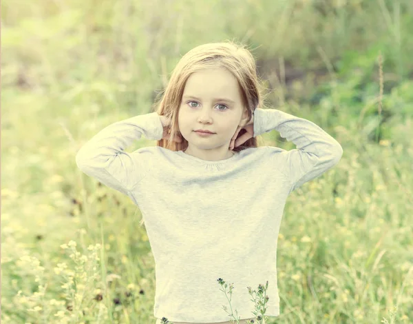 Enfant dans le champ parmi les fleurs et les herbes, souriant — Photo