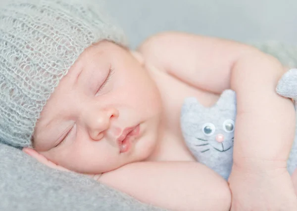 Słodkie noworodka w szary kapelusz z zabawkami — Zdjęcie stockowe