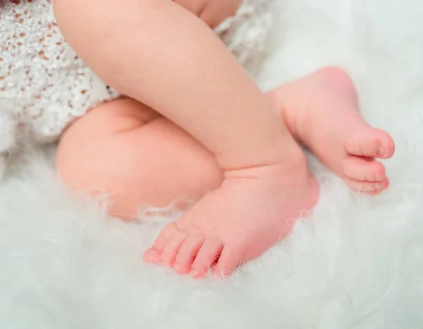Sweet baby legs folded on cot — стоковое фото