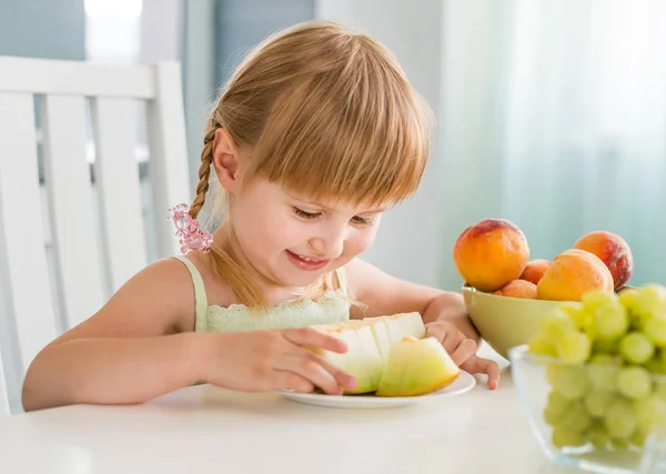 Schattig klein meisje met vruchten op tafel — Stockfoto