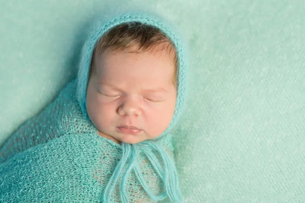 Portrait of sleepy newborn with wrapped head and body — Stock Photo, Image