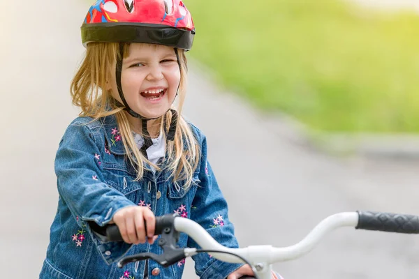 Linda menina no capacete e jaqueta de ganga em uma bicicleta — Fotografia de Stock