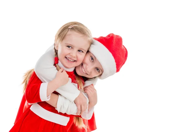 Twee gelukkige kleine meisjes in santa pakken omarmen — Stockfoto