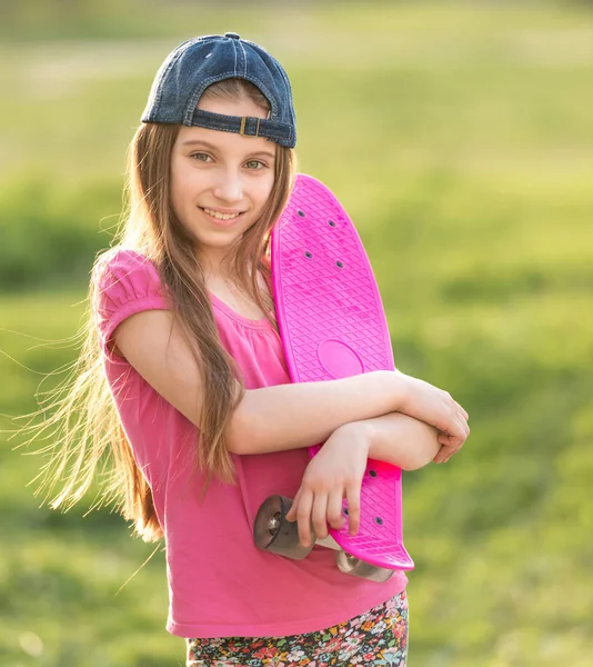 Tienermeisje holding haar roze bestuur — Stockfoto
