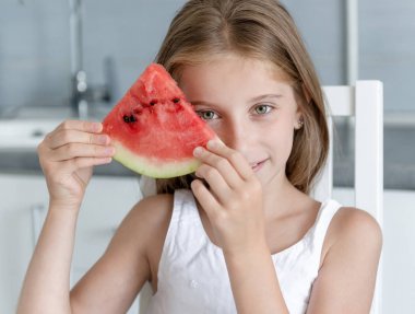 sevimli küçük kız mutfakta bir karpuz yiyor