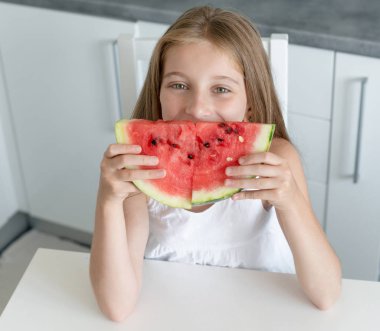 sevimli küçük kız mutfakta bir karpuz yiyor