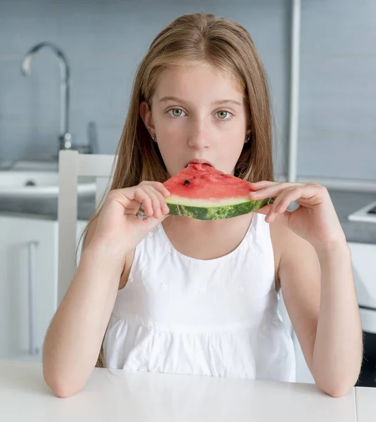Το χαριτωμένο μικρό κορίτσι τρώει ένα καρπούζι στην κουζίνα — Φωτογραφία Αρχείου