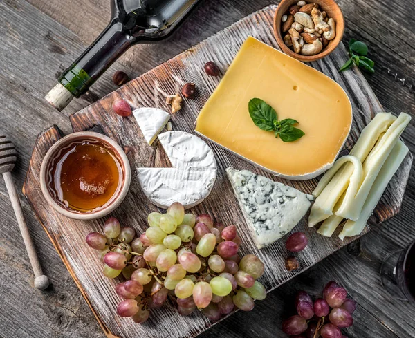 Plato de queso servido con vino, nueces y miel — Foto de Stock