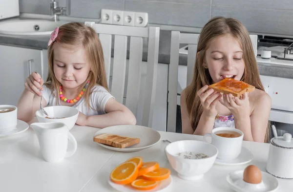 Systrarna äta brunch, havre och toast med honung — Stockfoto