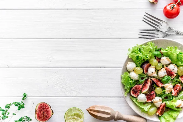 Salat mit Feigen, Mozzarella und Trauben auf weißem Holzgrund. — Stockfoto