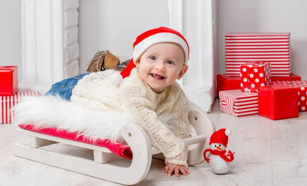 Sweet toddler in red hat on white sled — Stock Photo, Image