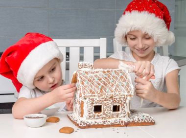 iki küçük kız kardeş Santa şapka yapımı bisküvi evi