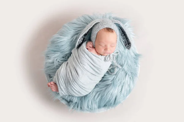 Bebé recién nacido en sombrero divertido durmiendo en una manta esponjosa, vista superior . — Foto de Stock