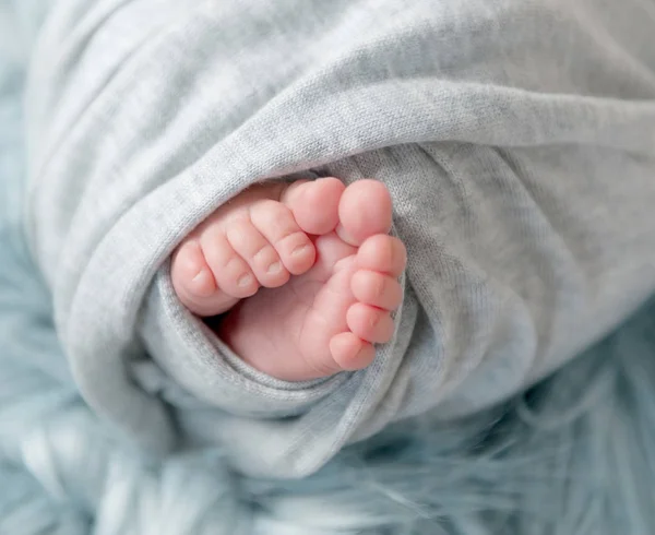 Nahaufnahme von nackten Füßen eines neugeborenen Babys im Karo. — Stockfoto