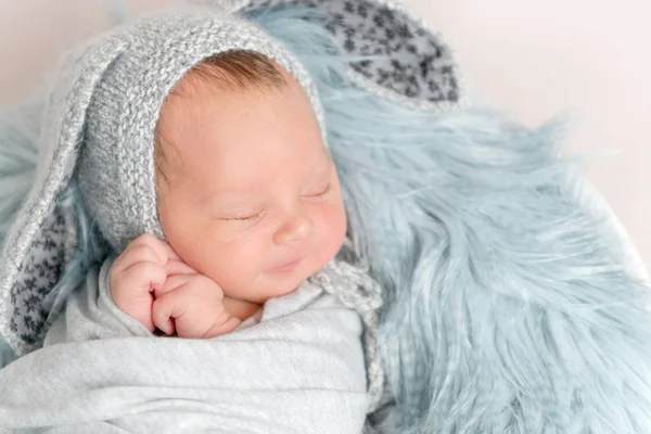 Nyfött barn i rolig hatt sover på fluffig filt, ovanifrån. — Stockfoto