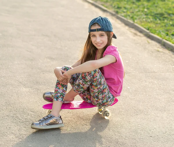 Girl with long hair sitting on skating board — Stock Photo, Image