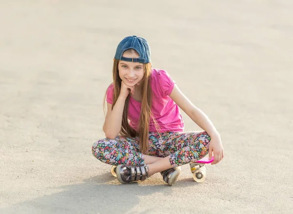 Meisje met lang haar zittend op schaatsen bestuur — Stockfoto
