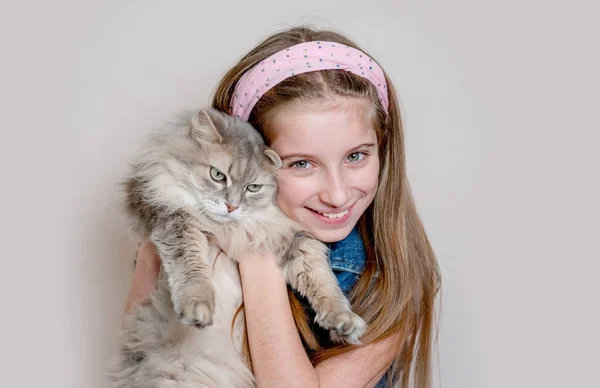 Menina positiva brincando com gato no fundo cinza — Fotografia de Stock