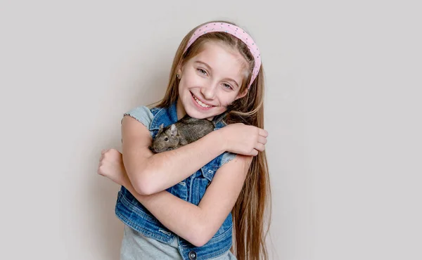 Niña sonriente sosteniendo un degu en sus brazos — Foto de Stock