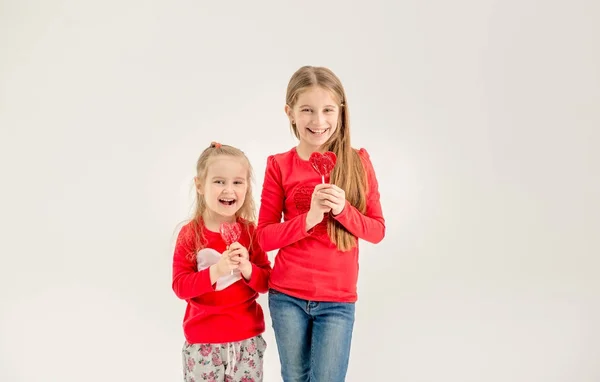 Two cute sisters with heart shaped lollipops — Stock Photo, Image