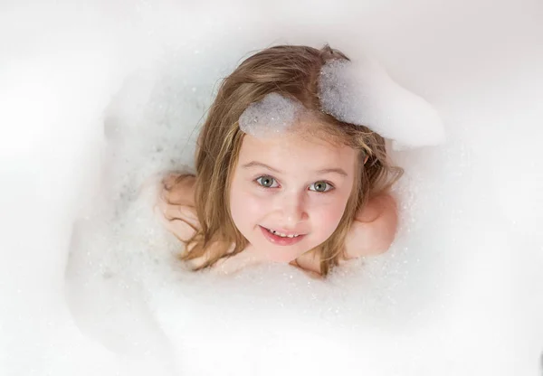 La bambina si bagna in un bagno con schiuma e bolle — Foto Stock