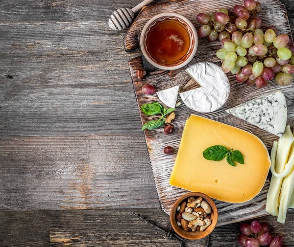 Cheese plate served with wine, nuts and honey — Stock Photo, Image