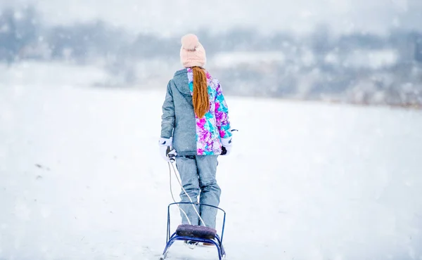 Petite fille marchant de retour à la colline le jour neigeux — Photo