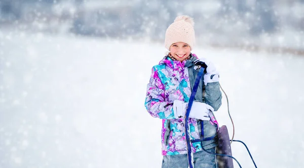 Fille en costume de ski tenant des traîneaux — Photo