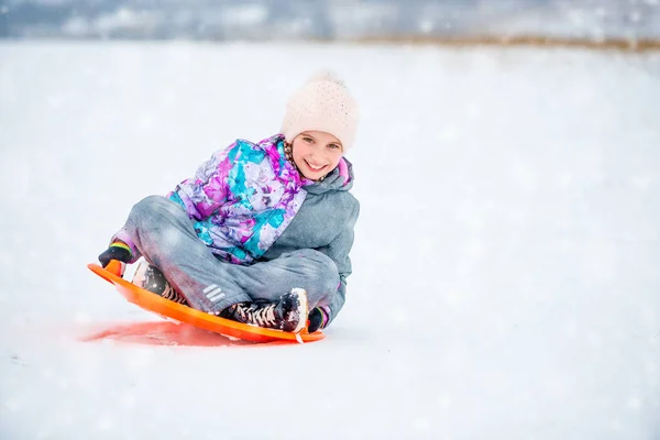 女孩在飞碟雪橇上滑下山坡 — 图库照片