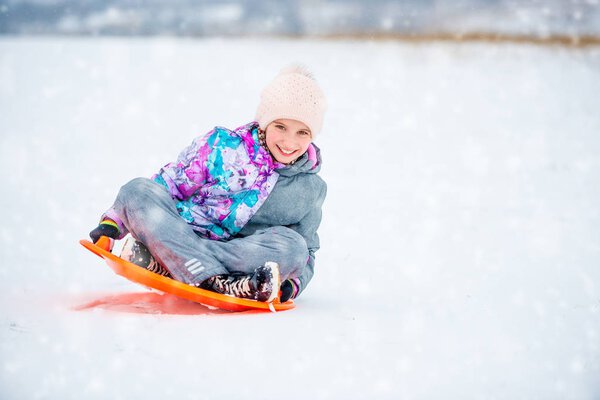 Girl sliding down the hill on saucer sled