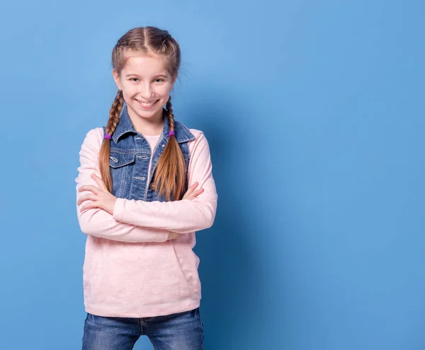 Teenager-Mädchen in selbstbewusster Pose vor blauem Hintergrund — Stockfoto